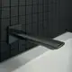 Schwarzer Wandauslauf von Ideal Standard an einer Wand mit schwarzen Fliesen, montiert über einer weißen Badewanne, mit eckiger Rosette und einfacher Linienführung.